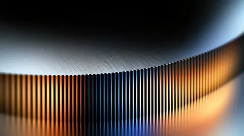 A curved wall of fine chrome ribs bends away from the viewer, lit warm amber on one side and cool silver on the other.