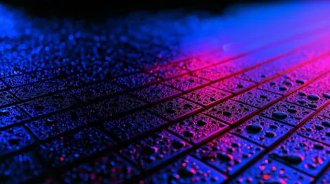 Water drops bead on a dark grid of tiles, washed in magenta and electric blue light.