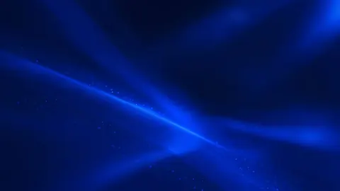 Soft beams of sapphire light cross through a blue haze dotted with faint specks.