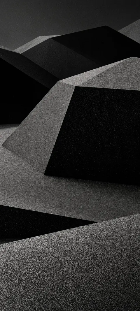 Folded graphite planes stack like origami dunes, sharp creases catching soft side light.